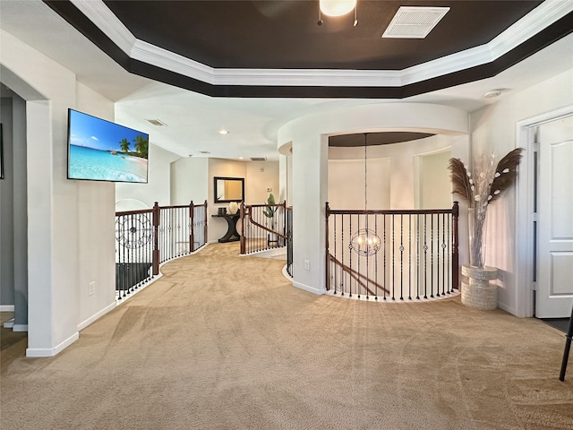 corridor featuring a tray ceiling, visible vents, an upstairs landing, and carpet flooring