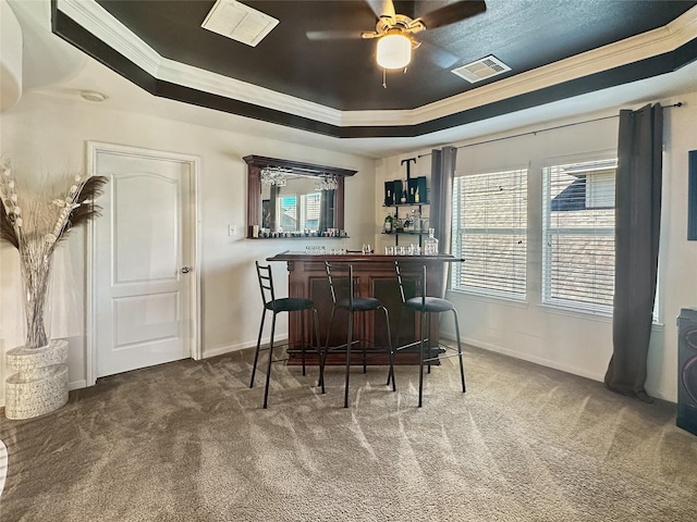 bar with visible vents, ornamental molding, carpet flooring, a bar, and a raised ceiling