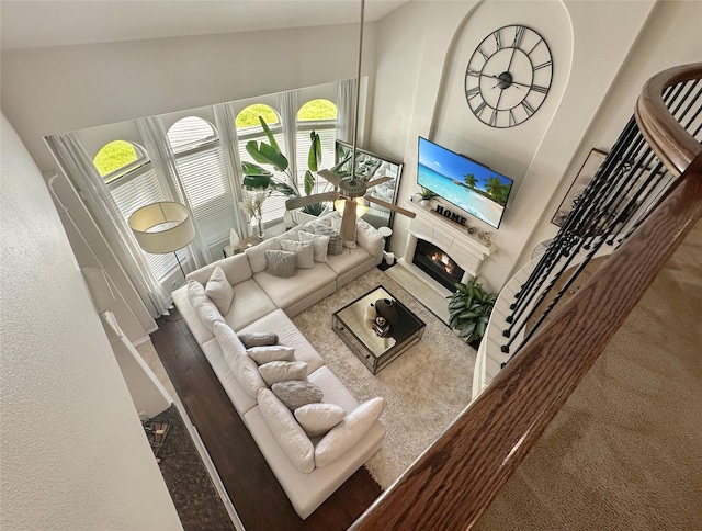 living room featuring a warm lit fireplace and a towering ceiling