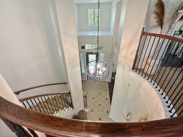 staircase with a chandelier and a towering ceiling