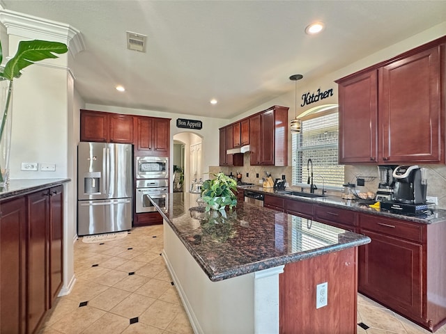 kitchen featuring visible vents, a sink, arched walkways, reddish brown cabinets, and appliances with stainless steel finishes