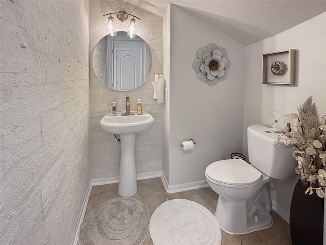 bathroom with baseboards, toilet, vaulted ceiling, and tile patterned flooring