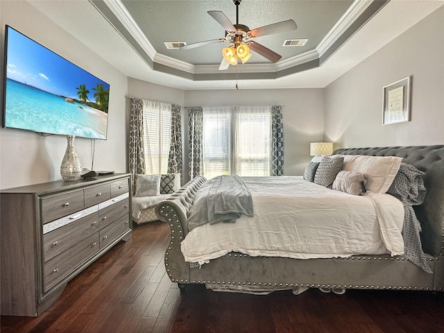 bedroom with visible vents, a ceiling fan, a tray ceiling, crown molding, and dark wood-style flooring