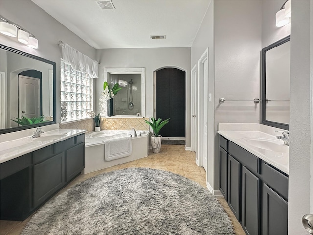 full bathroom featuring visible vents, a walk in shower, a garden tub, and a sink