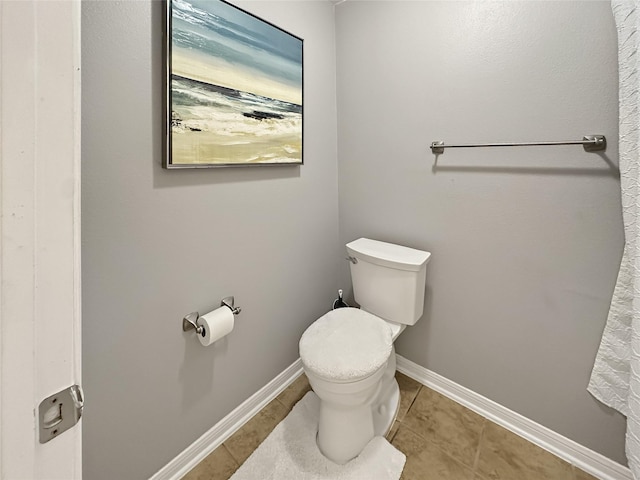 bathroom with tile patterned floors, toilet, and baseboards