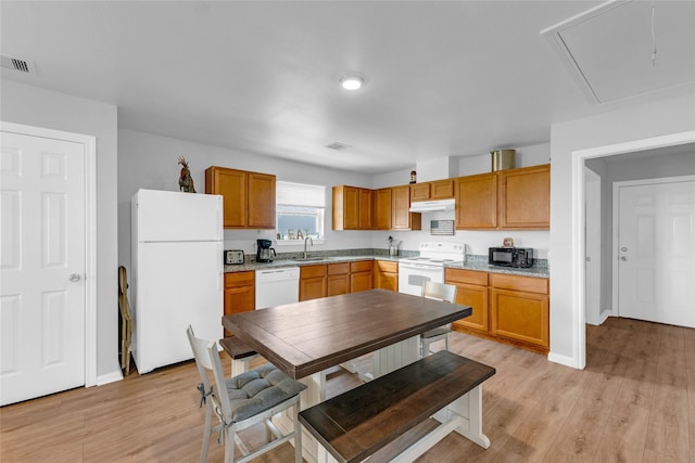 kitchen with white appliances, visible vents, a sink, light wood-style floors, and under cabinet range hood