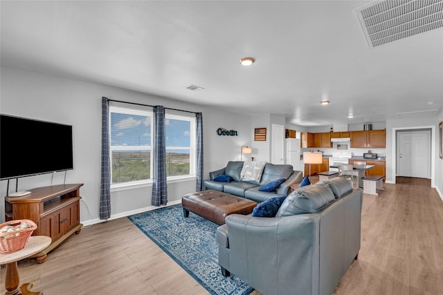 living area featuring baseboards, visible vents, and light wood-type flooring