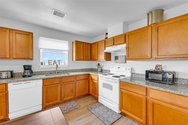 kitchen with white appliances, visible vents, a sink, light wood-style floors, and under cabinet range hood