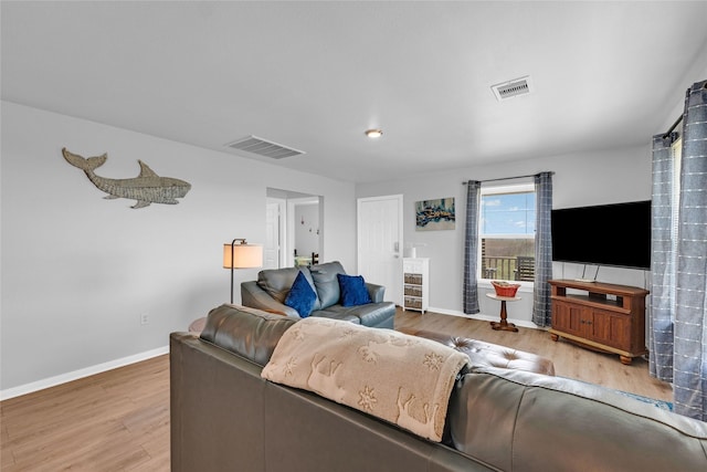 living room featuring visible vents, baseboards, and wood finished floors