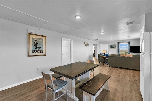 dining area with visible vents, attic access, baseboards, and wood finished floors