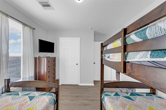 bedroom with wood finished floors, visible vents, and baseboards