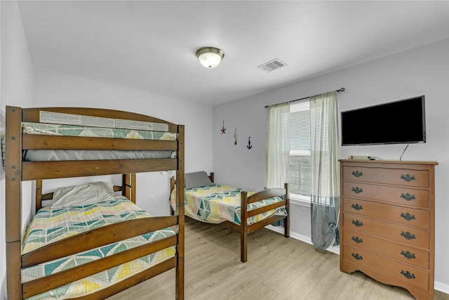 bedroom featuring visible vents, light wood-type flooring, and baseboards