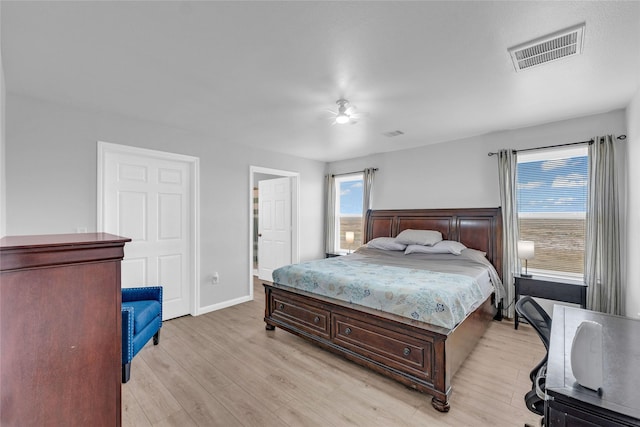 bedroom with visible vents, multiple windows, light wood-style flooring, and a ceiling fan