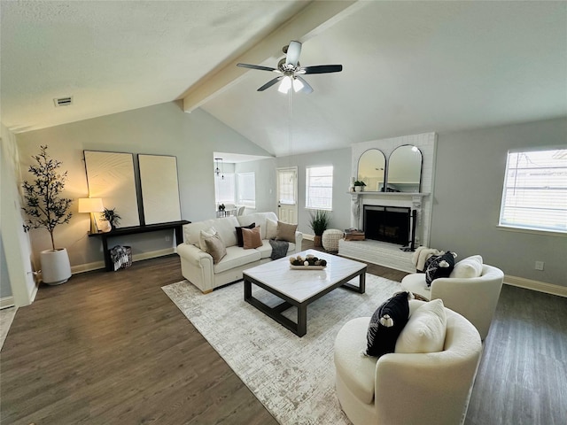 living area with lofted ceiling with beams, a fireplace, wood finished floors, and a ceiling fan