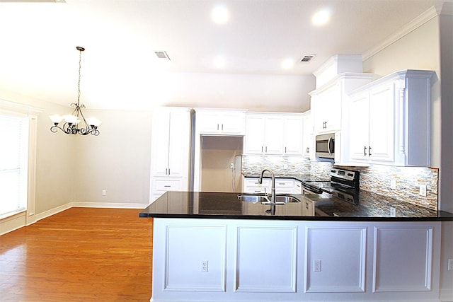 kitchen with stainless steel appliances, tasteful backsplash, visible vents, a sink, and a peninsula