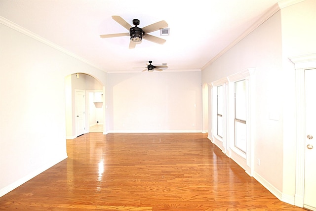 spare room featuring ornamental molding, arched walkways, visible vents, and light wood-style flooring