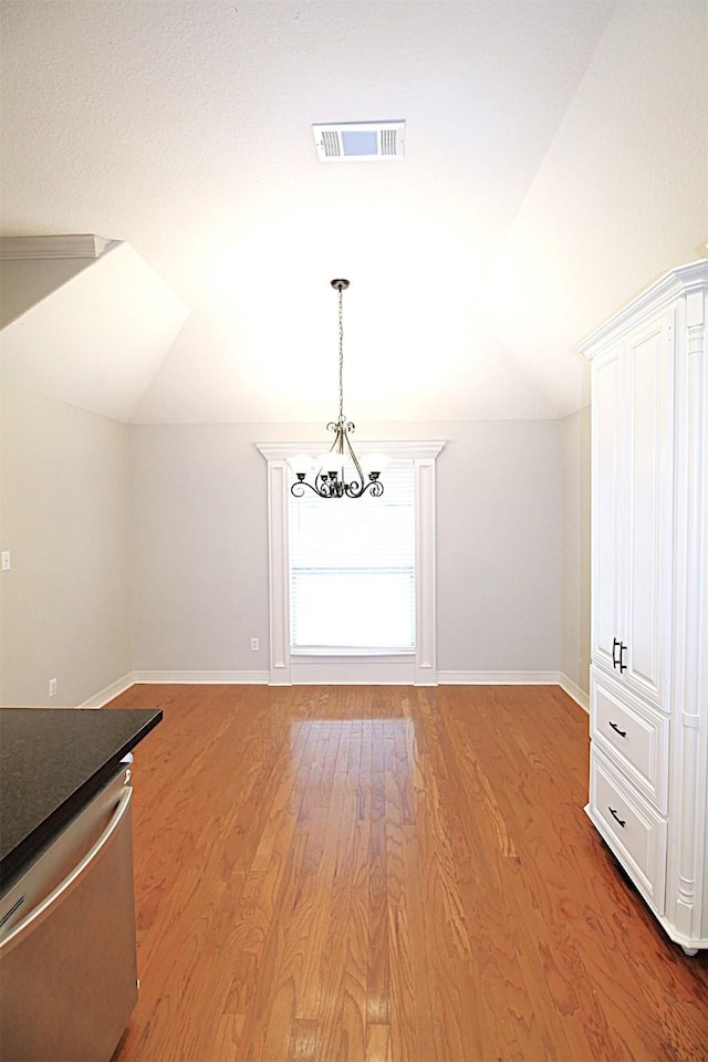 interior space featuring baseboards, visible vents, wood finished floors, an inviting chandelier, and vaulted ceiling