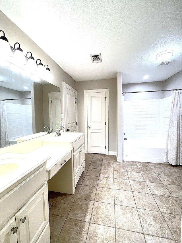 bathroom featuring double vanity, visible vents, tile patterned floors, a textured ceiling, and a sink