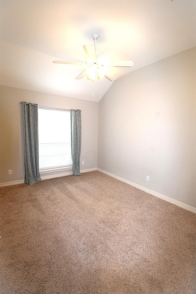 spare room featuring carpet floors, vaulted ceiling, baseboards, and ceiling fan