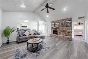 living area with a ceiling fan, a fireplace, lofted ceiling with beams, and wood finished floors