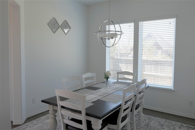 dining space featuring wood finished floors, baseboards, and an inviting chandelier