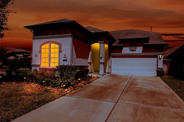 view of front of property with a shingled roof, driveway, and stucco siding