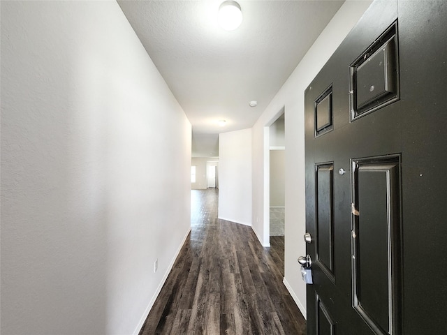 hallway featuring baseboards and wood finished floors