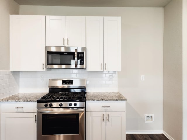 kitchen featuring light stone countertops, appliances with stainless steel finishes, white cabinets, and backsplash