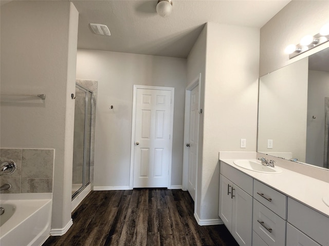 full bath featuring a stall shower, vanity, wood finished floors, baseboards, and a bath