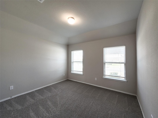 empty room featuring dark carpet and baseboards