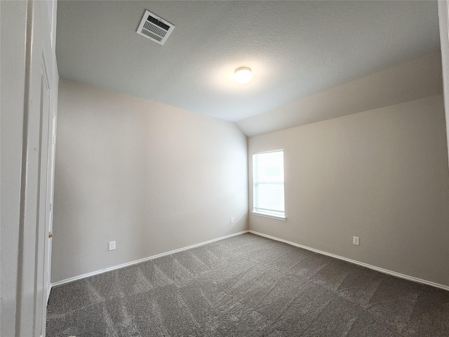 spare room with baseboards, vaulted ceiling, visible vents, and dark carpet