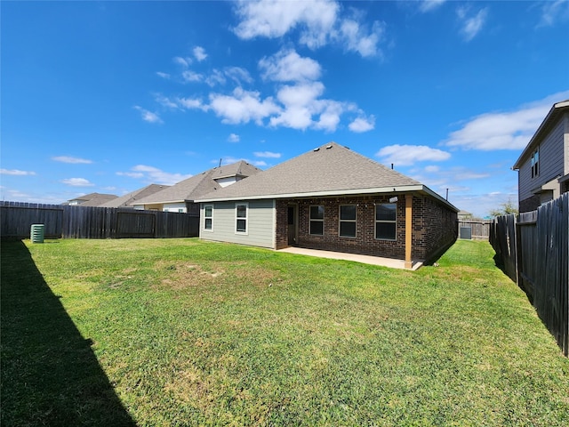 rear view of house featuring a yard, brick siding, a patio area, and a fenced backyard