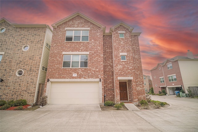 view of front of property featuring cooling unit, brick siding, an attached garage, and driveway