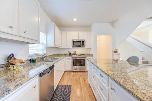 kitchen with white cabinets, stainless steel appliances, light wood-style floors, and a sink