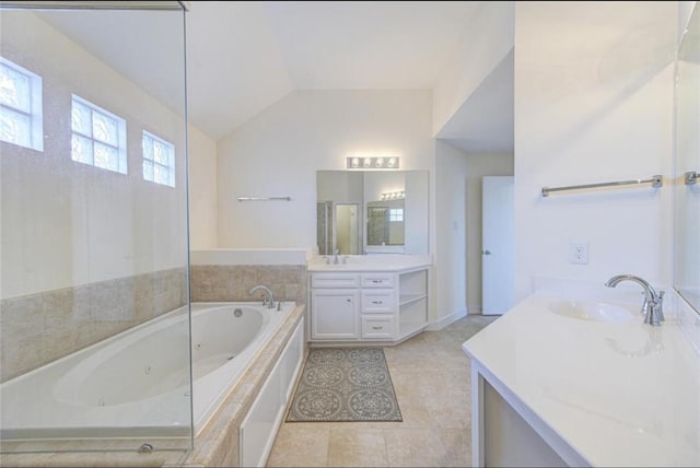 bathroom featuring a tub with jets, lofted ceiling, two vanities, a sink, and tile patterned flooring