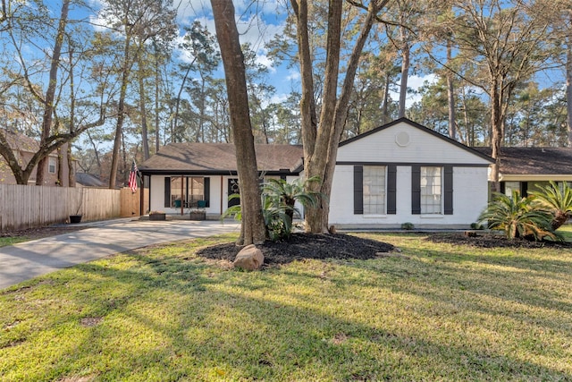 view of front facade featuring concrete driveway, a front lawn, and fence