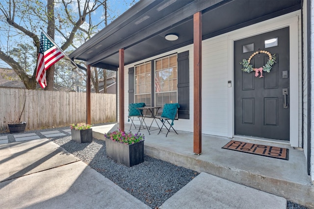 doorway to property featuring a porch and fence