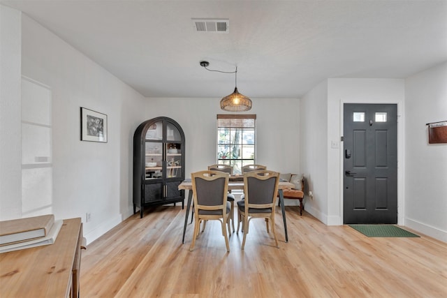 dining space featuring light wood-style floors, visible vents, and baseboards