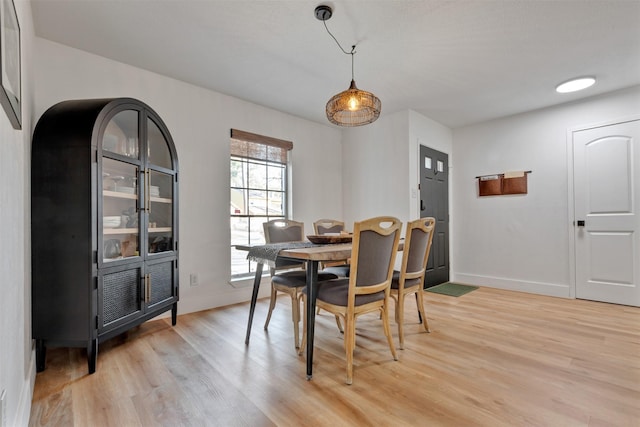 dining space with baseboards and light wood-type flooring