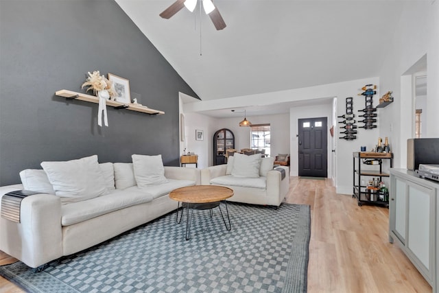 living room featuring baseboards, light wood-style flooring, high vaulted ceiling, and ceiling fan