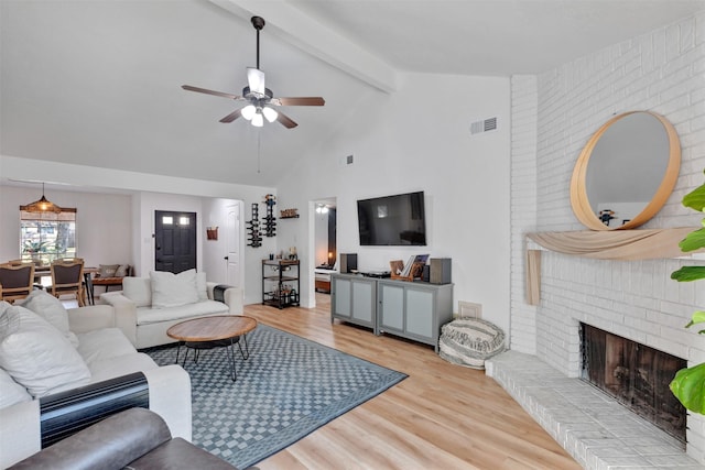 living room with wood finished floors, visible vents, beam ceiling, ceiling fan, and a brick fireplace