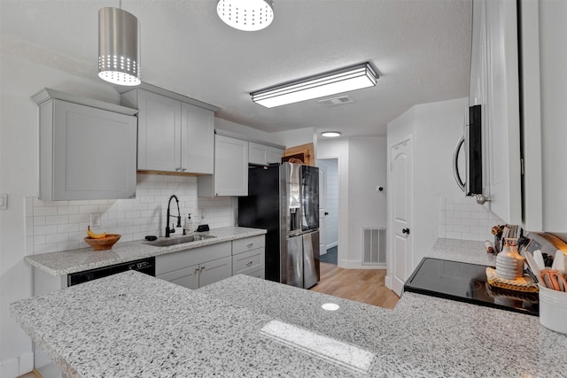 kitchen with visible vents, backsplash, stainless steel appliances, and a sink