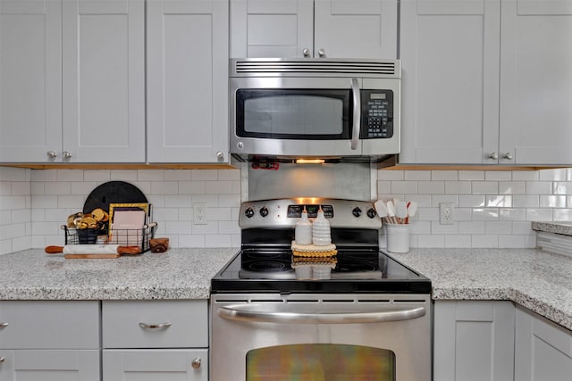 kitchen with light stone counters, backsplash, and appliances with stainless steel finishes