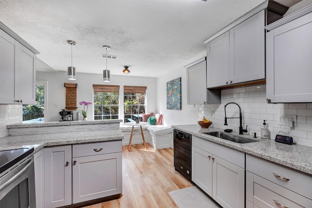 kitchen featuring visible vents, gray cabinets, a sink, light wood finished floors, and dishwasher