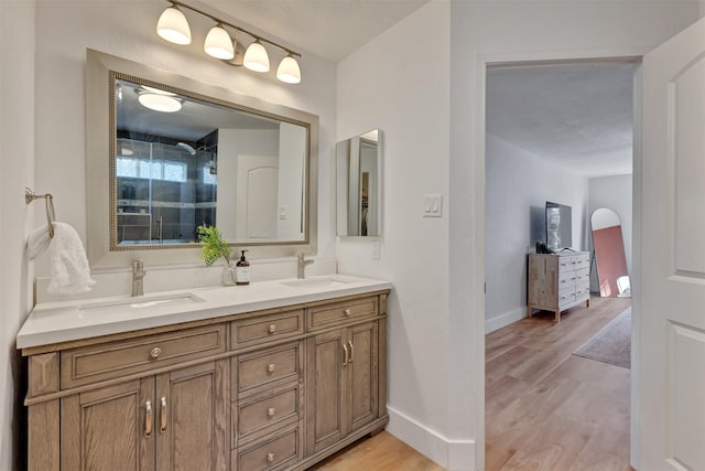 bathroom featuring double vanity, wood finished floors, baseboards, and a sink