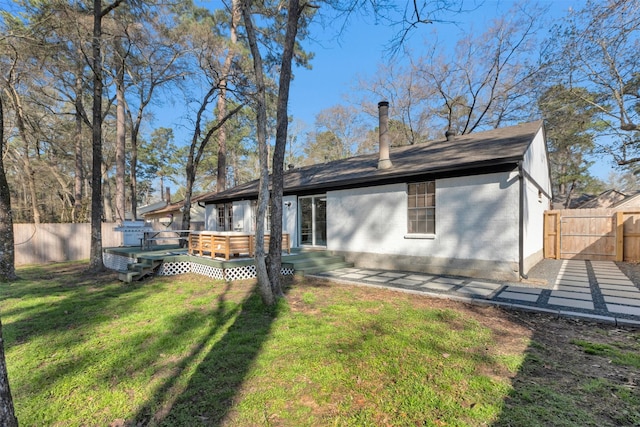 rear view of property featuring a yard, a fenced backyard, brick siding, and a wooden deck