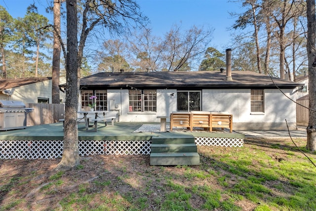 rear view of property with a wooden deck, brick siding, and fence