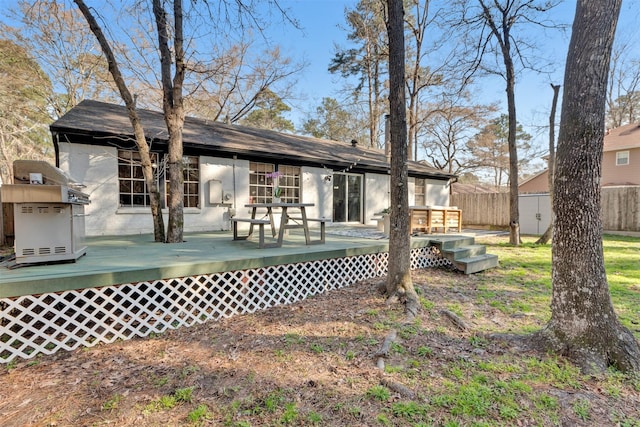 back of property with a wooden deck and fence