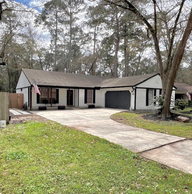 ranch-style house with concrete driveway, fence, a garage, and a front lawn