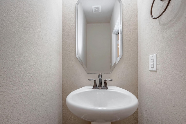 bathroom with a textured wall and a sink